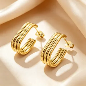 Close-up of elegant 18K gold plated multi-layer oval hoop earrings on beige satin fabric