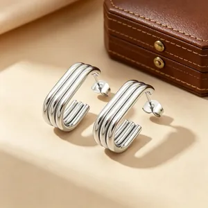 Macro shot of polished silver-tone triple-line elliptical stainless steel hoop earrings