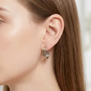 Close-up of a multi-layer silver and gold stainless steel hoop earring on a model's ear