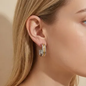 Close-up detail of stylish two-tone layered oval stainless steel earrings on model ear