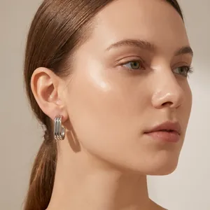 Close-up of triple-layered oval stainless steel earrings on a female model's ear