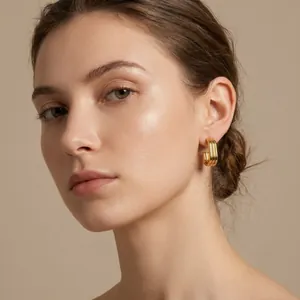 Detail shot of gold-plated stainless steel multi-layer ribbed hoop earrings on model.