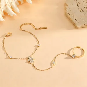 Gold plated titanium steel hand harness with Hamsa hand and evil eye charm detailing.