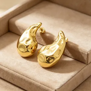 Primo piano di orecchini a goccia martellati in oro 18 carats in un portagioie elegante