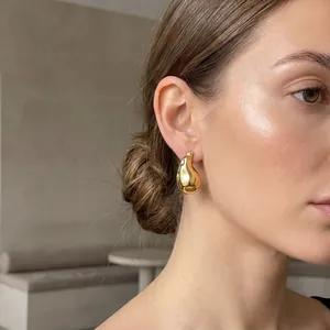 Dettaglio di orecchini a goccia martellati in acciaio placcato oro 18K su una modella