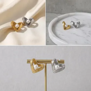 Makroansicht von gold- und silbernen herzförmigen Perlenohrringen mit elegantem Metalldesign