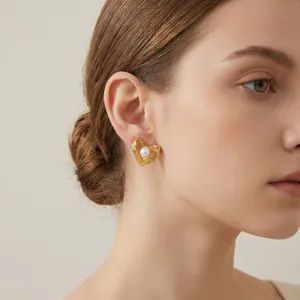 Detailansicht eines eleganten goldenen Herzohrrings mit Perleneinlage am Ohr eines Models.