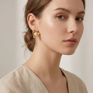 Detailansicht eleganter goldener Herz-Ohrringe mit Perlen, getragen von einem Model