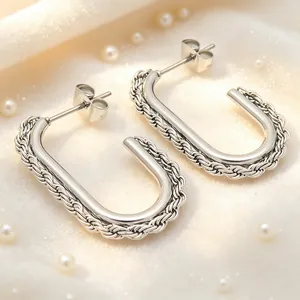 Close-up detail of stainless steel rectangular hoop earrings with twisted rope texture.