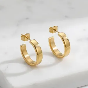 Detailed macro view showing the texture of minimalist golden C-shaped hoop earrings