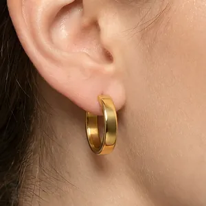 Close-up of minimalist gold stainless steel C-shaped hoop earrings on ear lobe