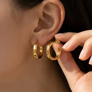 Detailed view of elegant gold-tone stainless steel C-shaped hoop earrings on model ear