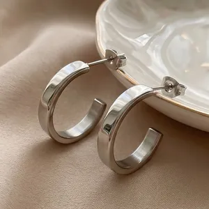 Detailed macro view of minimalist polished stainless steel C-shaped hoop earrings