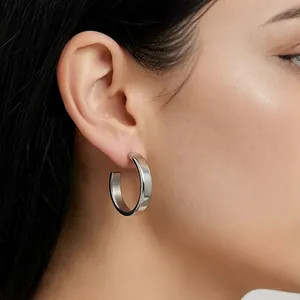 Detailed view of a minimalist silver stainless steel C-shaped hoop earring worn on ear