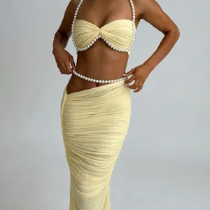 Detailansicht eines hellgelben Sets aus Perlen-Bandeau-Top und gerafftem Maxirock-Design