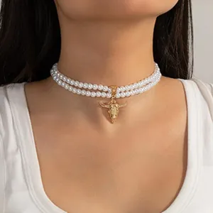 Vista dettagliata di una collana girocollo a due fili di perle con pendente a testa di toro d'oro