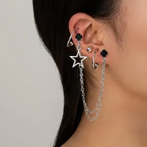 Primo piano del set di orecchini con catena a stella e ear cuff in argento su modella