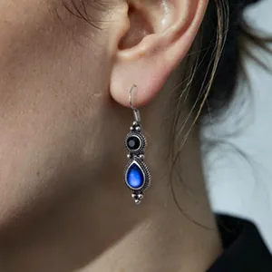 Dettaglio di orecchini etnici in argento con goccia blu e pietre nere in stile retrò