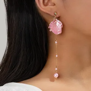 Primo piano di un orecchino pendente con petali rosa e perle indossato da una modella