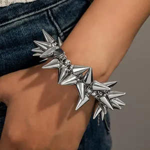 Dettaglio ravvicinato di un bracciale punk argento con borchie a cono metalliche sul polso