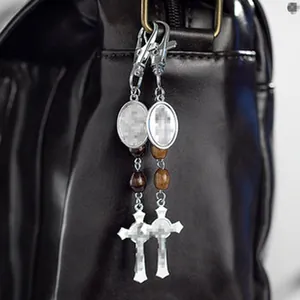 Dettaglio di pendente etnico vintage con croce e perle di legno su borsa nera