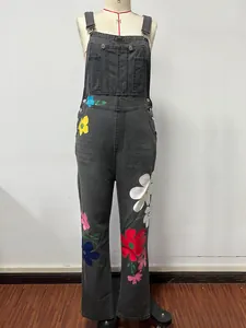 Detailed front view of black denim overalls with colorful floral prints on mannequin