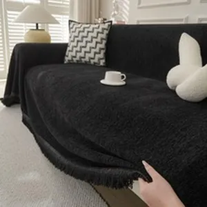 Close-up of black bohemian chenille sofa cover with decorative fringe details.