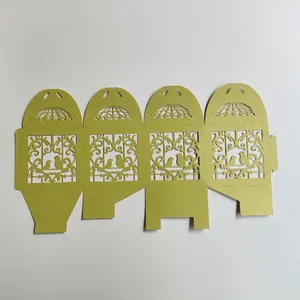 Flat-lay view of golden laser-cut wedding favor box with romantic bird cage patterns