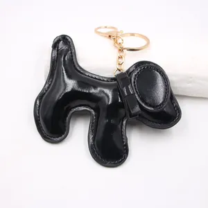 Detail view of a glossy black PU leather dog bag charm with gold-toned metal hardware