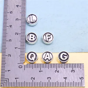 Size comparison of silver alloy alphabet beads for DIY jewelry making charms.