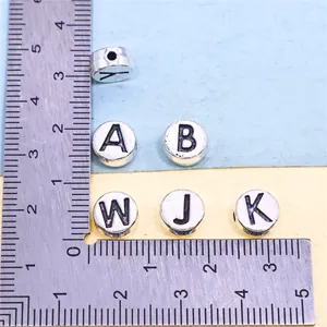 Detailed view of alloy alphabet beads with ruler for scale, approximately 7mm size