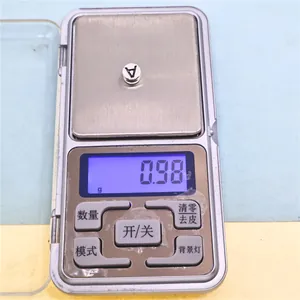 Close-up detail of a silver alloy alphabet letter V charm on a precise digital jewelry scale