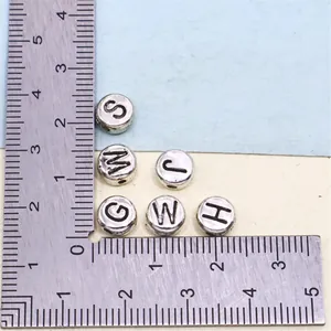 Macro detail shot of silver alloy alphabet beads with a metal ruler for size reference