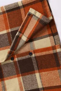 Close-up detail of orange plaid flannel shirt featuring dark buttons and soft fabric texture