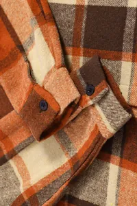 Close-up detail of a men's orange and brown plaid flannel shirt cuffs featuring black buttons