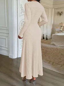 Elegant back view of a textured cream long-sleeved maxi dress in a chic room setting