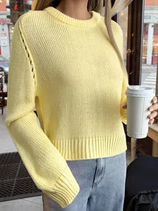 Gros plan d'un pull en tricot jaune clair à manches longues pour femmes dans un café.