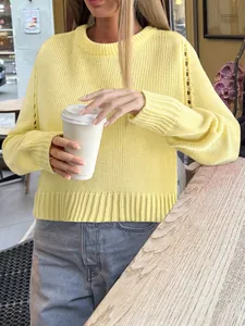 Détail rapproché d'un pull en tricot jaune à manches longues dans un café en plein air