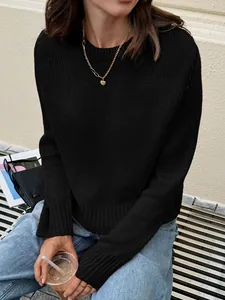 Gros plan d'un pull en maille noire à manches longues avec un collier coeur doré