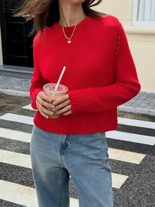 Vue style de rue d'un pull en maille rouge vif à manches longues avec un jean bleu.