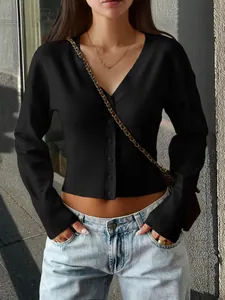 Close-up detail of a women's black V-neck buttoned knitted cardigan with ribbed waist