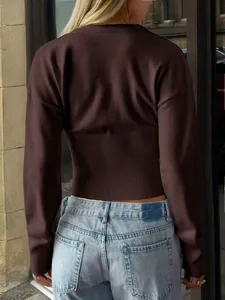 Back view of a brown ribbed waist knitted sweater paired with light blue denim jeans.