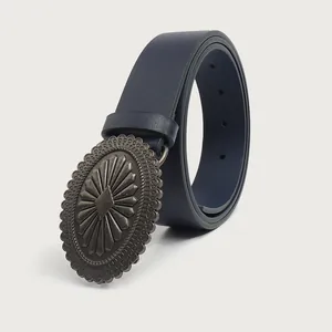 Close-up detail of vintage navy blue belt featuring a large ornate carved alloy buckle.