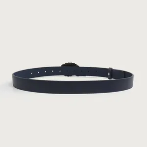 Macro detail showing vintage women's leather belt with carved alloy buckle in navy blue