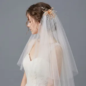Elegant bridal veil with gold floral pearl hair ornament shown on a white wedding dress