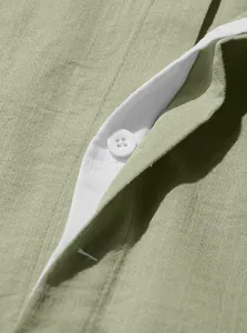 Macro detail of olive green linen shirt button and placket stitching