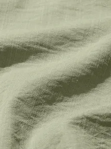 Close-up macro view of the breathable linen fabric texture of the light green shirt.