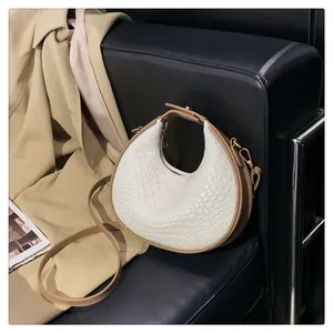 Close-up detail of a stylish white woven crescent hobo bag placed on a black leather sofa