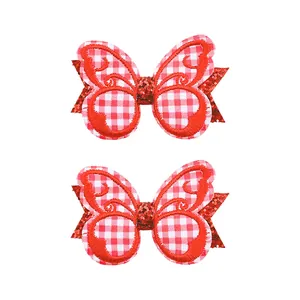 Gros plan de barrettes papillon brodées vichy rouge et blanc avec support pailleté
