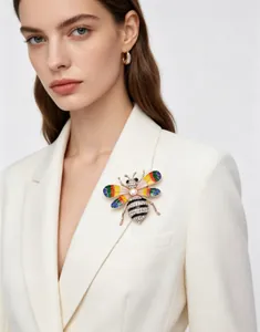 Vue détaillée d'une broche abeille en strass colorés sur le revers d'un blazer blanc élégant